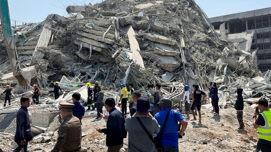 pessoas-ficam-perto-do-local-de-um-predio-que-desabou-apos-um-forte-terremoto-atingir-o-centro-de-mianmar-na-sexta-feira-1743154447176_v2_900x506 Terremoto em Mianmar e Tailândia: Imagens Chocantes Mostram Antes e Depois da Tragédia